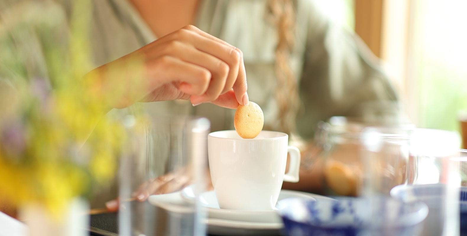 Hand som doppar kaka i kaffekopp